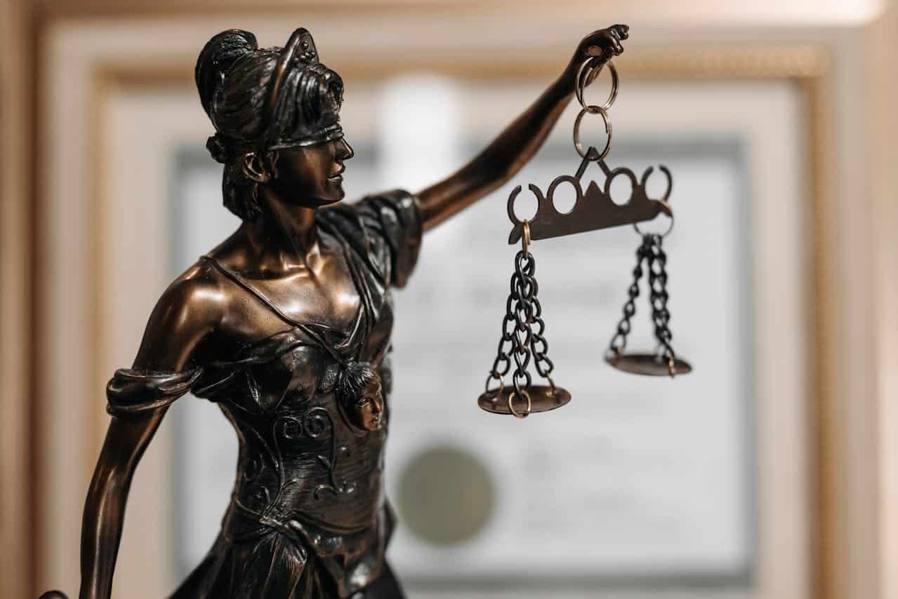 Image is of a Lady Justice statue holding balanced scales, concept of a criminal defense lawyer advocating for fairness, due process, and the rights of the accused.